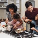 Family cooking together at home during a summer staycation, enjoying family activities and family bonding while building self-reliance.